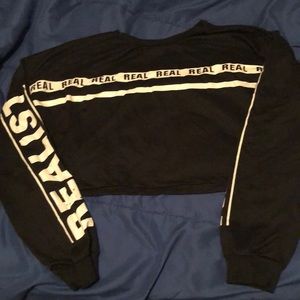A black and white crop top shirt that says real